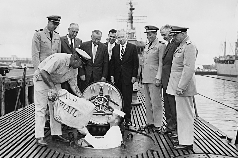 Postmaster General Arthur Summerfield, fourth from left, postal officials and U.S. Navy personnel watch the loading of “missile mail” into the Navy submarine USS Barbero.