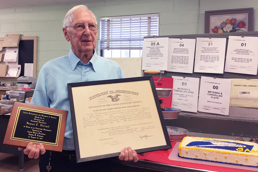 At his Jan. 31 retirement party, Samuel J. Mitchell displays a plaque and certificate he received when President Lyndon Johnson appointed him Postmaster of Philo, OH.