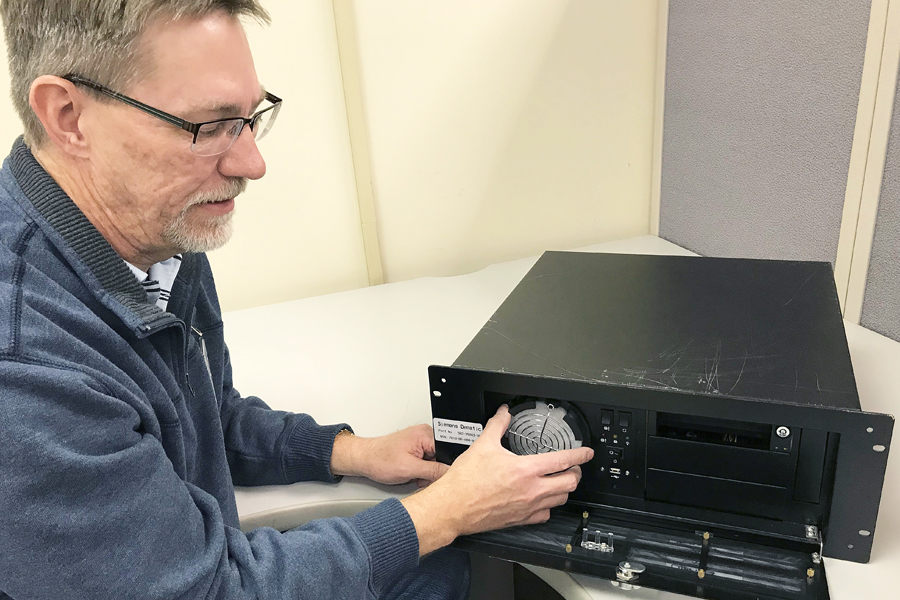 Ward Bengtson, a senior technician at the Central Repair Facility in Topeka, KS, handles a 3-D printed replacement part for mail processing equipment.